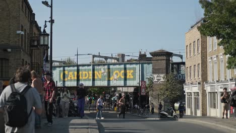 Street-Artwork-At-Camden-Lock-Bridge-With-People-On-Busy-High-Street-At-Daytime-In-London,-UK