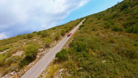 Filmische-Luftaufnahme-Eines-Klassischen-Roten-Mustangs,-Der-Auf-Einer-Malerischen-Autobahn-Durch-Die-Hügel-Spaniens-Fährt