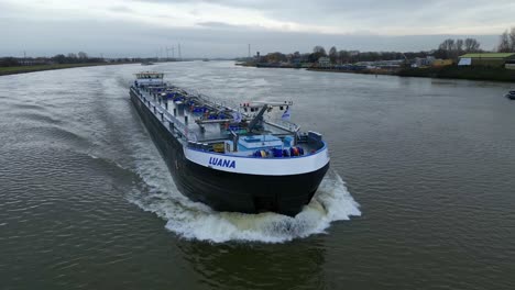Backwards-drone-panning-shot-of-a-bunker-barge-sailing-on-full-speed-over-the-dutch-river