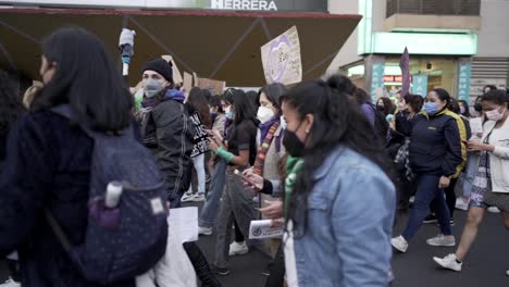 Frauen-Marschieren-Und-Halten-Während-Des-Internationalen-Frauentags-In-Quito,-Ecuador,-Schilder-Und-Fahnen-Mit-Protestphrasen-Hoch
