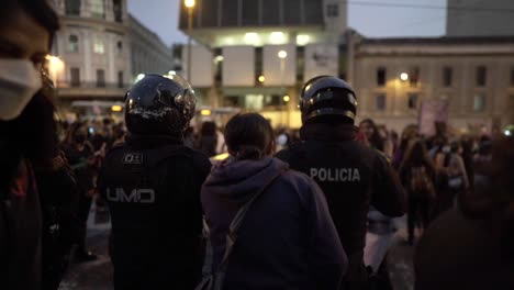 Eine-Frau-Springt-Und-Singt-Direkt-Neben-Polizisten,-Die-Vor-Einer-Gruppe-Von-Frauen-Stehen,-Die-Während-Einer-Protestaktion-Zum-Internationalen-Frauentag-In-Quito,-Ecuador,-Marschieren