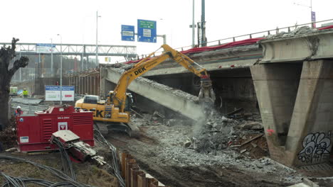 Demolition-machine-dismantling-collapsed-concrete-highway-bridge-block