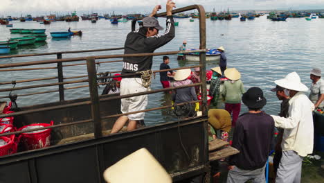 Pescadores-Y-Mujeres-Cargan-Cestas-De-Pescado-En-Camiones-De-Transporte-En-La-Playa-De-Mui-Ne