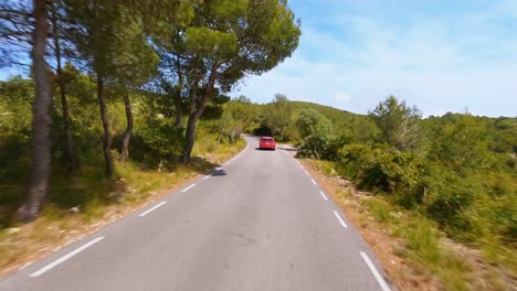 Antena-Escénica-De-Fpv-Siguiendo-Un-Automóvil-Rojo-Que-Conduce-A-Través-Del-Pintoresco-Paisaje-Montañoso-En-España