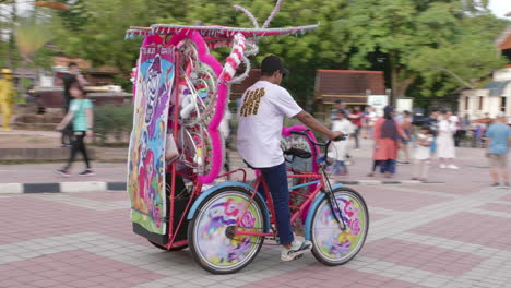 Rider-departs-in-pink-trishaw-decorated-with-cute-ponies,tracking-shot