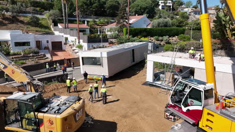 Construction-site-of-modular-home-with-heavy-equipment,-aerial-drone-view