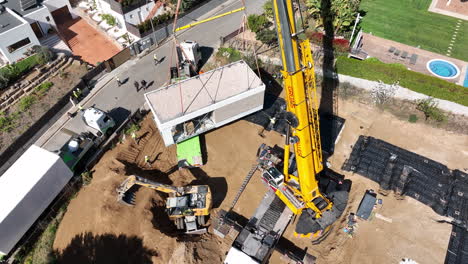 Industrial-crane-lifting-modular-home-block,-aerial-view