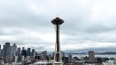 Aerial-orbit-of-Space-Needle-overlooking-the-city-of-Seattle,-Washington-on-a-cloudy-day