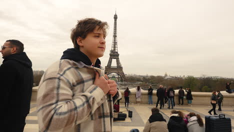 Young-caucasian-European-man-adjusting-his-jacket-in-slow-motion-with-Eiffel-Tower-behind-him