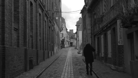Grayscale-Scenic-View-Of-An-Adult-Person-Walking-On-The-Honfleur-Old-Town-Street-In-Normandy,-France