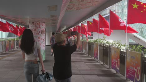 A-man-takes-photos-of-Chinese-and-Hong-Kong-flags-flowing-in-the-wind-during-China's-National-Day,-the-founding-anniversary-of-the-People's-Republic-of-China