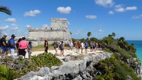 Tourists-visiting-The-Castle-mayan-ruins-at-Tulum-archeological-site,-Quintana-Roo,-Mexico