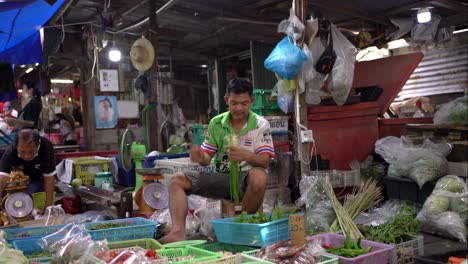 Vendors-man-fresh-vegetable-stalls-are-packing-and-weighing-vegetables-in-Maeklong-Railway-Market,-a-unique-and-fascinating-attraction-in-Samut-Songkhram-province,-Southwest-Bangkok,-Thailand
