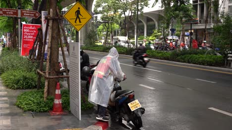 Motorcycle-taxi-driver-wearing-raincoats-on-rainy-days-parked-his-bike-in-Silom,-Bangkok,-Thailand