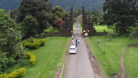 Luftaufnahmen,-Touristen-Stehen-In-Der-Schlange,-Mädchen-Posieren-Für-Ein-Foto-Am-Tor-Des-Handara-Resorts,-Berühmte-Ikonische-Touristenattraktion-In-Bali,-Indonesien