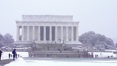 Gente-Caminando-Frente-Al-Monumento-A-Lincoln-En-Un-Clima-Frío-De-Nieve