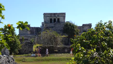 People-walikng-around-The-Castle-at-Tulum-archeological-site,-Quintana-Roo,-Mexico