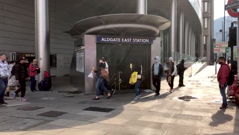 People-walk-past-the-entrance-to-the-Aldgate-East-Station-in-London,-UK