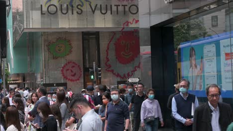 Pedestrians-and-shoppers-are-seen-at-a-traffic-light-in-front-of-the-French-luxury-fashion-brand-Louis-Vuitton-store