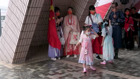 Ein-Junges-Mädchen-Spürt,-Wie-Der-Regen-Fällt,-Während-Pro-China-Anhänger-In-Kostümen-Der-Han-Dynastie-Am-Chinesischen-Nationalfeiertag-Zuflucht-Vor-Dem-Regen-Suchen