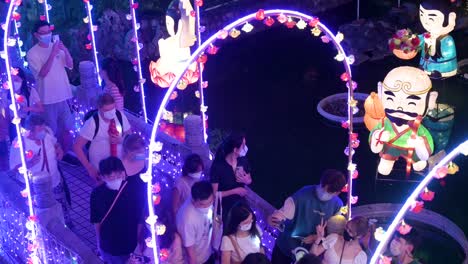 Chinesische-Besucher-Gehen-über-Eine-Mit-Lichtern-Geschmückte-Brücke,-Machen-Selfies-Und-Genießen-Während-Des-Mittherbstfestes-Eine-Nächtliche-Laternenshow-Im-Wong-Tai-Sin-Tempel