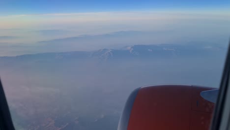 Blick-Aus-Dem-Flugzeugfenster-Auf-Den-Düsenmotor,-Im-Hintergrund-Können-Wir-Wolken,-Boden-Und-Berge-Sehen