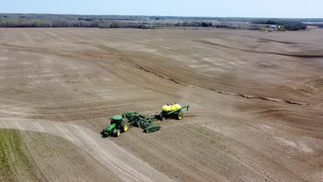 Drone-view-of-a-John-Deere-tractor-and-air-seeder-planting-a-field-on-a-sunny-dry-spring-day-in-Northern-Ontario