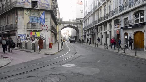 Menschen,-Autos-Und-Eine-Gelbe-Straßenbahn-Am-Cais-Sodre,-Im-Zentrum-Von-Lissabon,-Portugal,-Während-Menschen-Vorbeigehen
