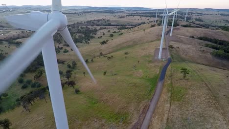 Drone-tracks-back-from-wind-farm-to-reveal-turbine-with-blades-passing-close-to-camera