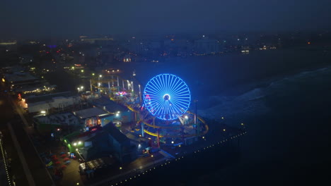 Aerial-view-around-the-Pacific-park-on-Santa-Monica-pier,-foggy-evening-in-LA,-USA