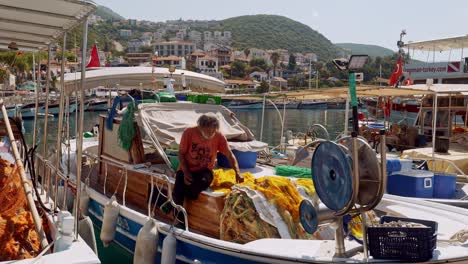 Turkish-fisherman-mending-his-nets-onboard-his-bobbing-boat-in-Kac-harbour