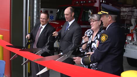 Dignitaries-at-ribbon-cutting-ceremonies-at-a-fire-hall-with-big-scissors