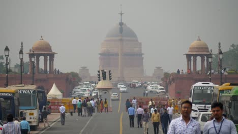 Busy-road-of-Kartavya-Path-during-parliament-session,-people-walking-across-the-busy-street,-New-Delhi-poor-air-quality,-low-visibility,-grey-smog-sky,-India