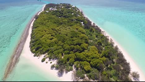 Drone-slowly-flies-up-from-beach-to-reveal-island-surrounded-by-clear-waters-and-reef