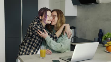 Pregnant-lesbian-woman-embracing-her-partner-on-kitchen