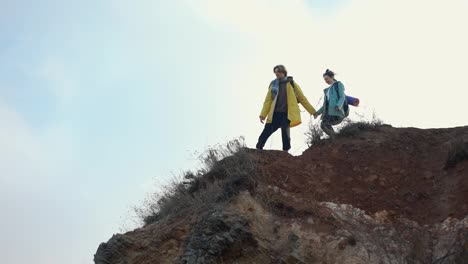 The-active-man-and-woman-walking-on-rocks-with-backpacks
