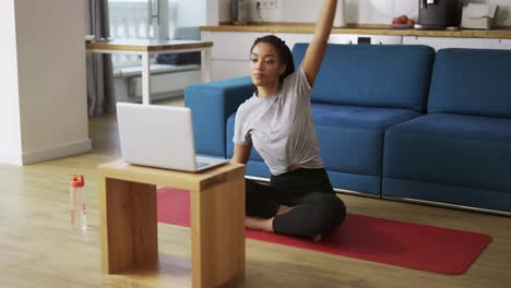 Young-African-woman-doing-stretching,-warming-up-her-joints-in-front-laptop,-slow-motion