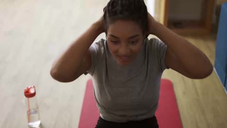 Young-African-American-female-athlete-working-out-in-the-living-room,-fall-tired-on-mat