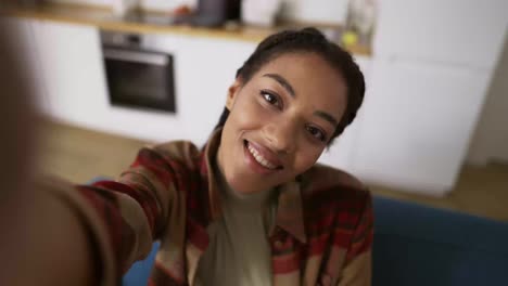 pointe-of-view-shot-of-Afro-American-girl-taking-selfie-smiling-posing-looking-at-camera-at-home-alone