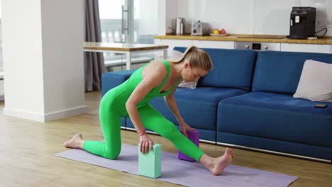 Woman-stretching-legs-with-yoga-blocks-in-living-room-at-home