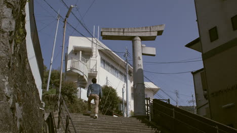 Hombre-Subiendo-Escaleras-Con-El-Santuario-Sanno-En-La-Cima-En-Nagasaki,-Japón