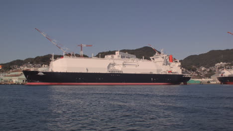 Sailing-past-tanker-docked-at-Kobe-Port,-Japan