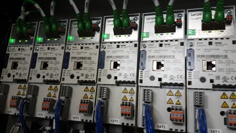 CLOSE-UP-shot-from-right-to-left-of-a-series-of-industrial-inverter-drives-with-flickering-green-leds-in-a-electrical-cabinet-of-a-running-machine