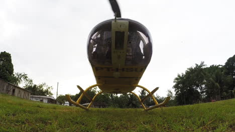 Helicopter-is-taking-off-from-grassy-field,-turns-around-a-flies-away