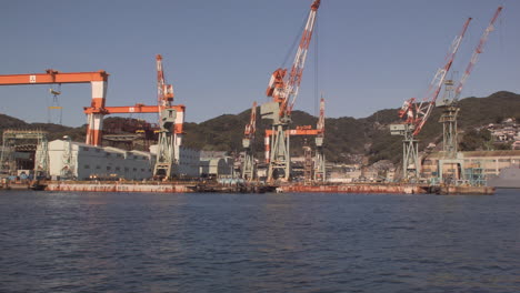 Sailing-past-port-gantry-cranes-at-Kobe-Port,-Japan
