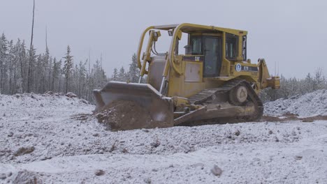 Student-bulldozer-operator-pushes-snow-covered-dirt-on-jobsite