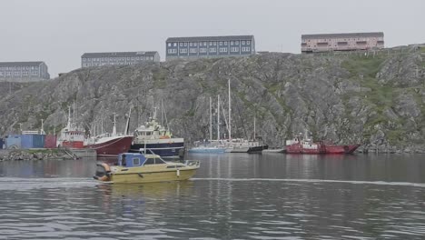 Boot-Fährt-Am-örtlichen-Hafen-In-Nuuk-Vorbei,-Mit-Wohnhäusern-Im-Hintergrund-Auf-Einer-Klippe