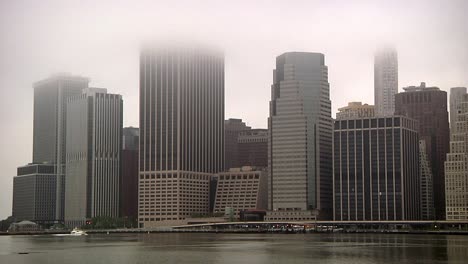 Blick-Auf-Die-Skyline-Von-Lower-Manhattan-Und-Pier-11-Während-Eines-Nebligen-Morgens-Mit-Vorbeifahrendem-Boot-Auf-Dem-East-River