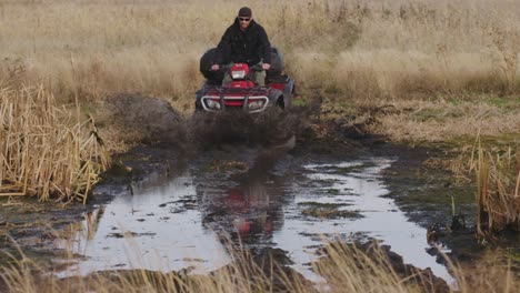 ATV-rider-hitting-mud-swamp-at-high-speed-towards-camera