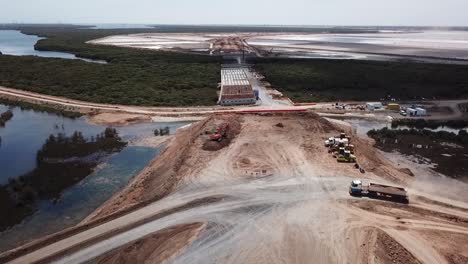 Aerial-shot-of-a-truck-driving-on-a-construction-site-near-wet-lands